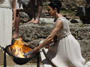 A high priestess, lights the Olympic flame using a concave mirror to concentrate the sun`s rays, in the final dress rehearsal for the lighting of the flame held in Ancient Olympia, Greece.