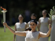 A high priestess, holding a lit torch and an olive branch, performs during the final dress rehearsal for the lighting of the Olympic flame held in Ancient Olympia, Greece.