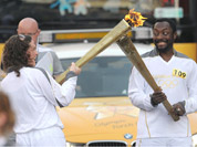 Will.i.am of the Black Eyed Peas passes the Olympic Flame to torchbearer Emma Fowler in Taunton, England.
