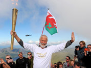 Sir Chris Bonington holding the Olympic Flame on the top of Mount Snowdon in Wales during the Olympic Torch Relay.