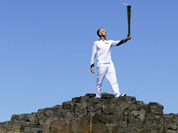 Peter Jack holds the Olympic torch aloft at the Giant`s Causeway in county Antrim, Northern Ireland.