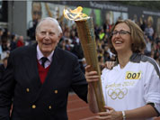 The Olympic Flame is passed between Sir Roger Bannister and Oxford doctoral student Nicola Byrom on the running track at Iffley Road Stadium in Oxford, England.