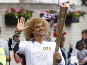 This image made available by LOCOG shows former Colombian soccer player Carlos Valderrama carrying the Olympic Flame on the Torch Relay leg between Slough and Windsor, England.