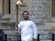Torchbearer Abdul Kasam carries the Olympic torch at the Tower of London. The Opening Ceremony of the London Olympic Games is on Friday, July 27, 2012.