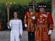 British retired champion Dame Kelly Holmes pose for the photographers with the Olympic flame at the Tower of London.