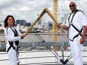 The photo provided by LOCOG shows torchbearers Nadia Comaneci, left, and John Amaechi as they handing over the light of the Olympic Torch on the viewing platform of the North Greenwich Arena, London.