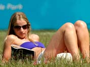 Sinead Galvin, of London, reads a magazine outside an Olympic merchandise store in Hyde Park in London.