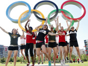 Basketball team members from Canada jump in the air in front of the Olympic rings inside the London 2012 Olympic Village in Stratford.