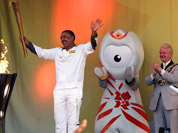 In this photo provided by LOCOG, torchbearer 153 Daley Thompson acknowledges the crowd after lighting the cauldron at the end of Day 68 in the Torch Relay in London.