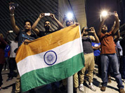 Men hold the national flag of India as they take photographs of fireworks from a neighborhood outside the Olympic Park during the 2012 Summer Olympics Opening Ceremony in London. 