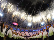 Athletes and volunteers watch a fireworks display after the Olympic cauldron was lit during the Opening Ceremony at the 2012 Summer Olympics in London.