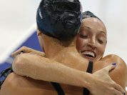 United States` Claire Donahue, right, embraces United States` Dana Vollmer after competing in the women`s 100-meter butterfly swimming semifinal at the Aquatics Centre in the Olympic Park during the 2012 Summer Olympics in London.
