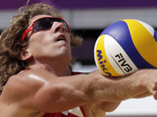 Aleksandrs Samoilovs of Latvia sets the ball during a beach volleyball match against the Republic of South Africa at the 2012 Summer Olympics in London.
