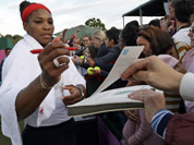 Serena Williams of the United States signs autographs after a doubles match at the All England Lawn Tennis Club in Wimbledon, London at the 2012 Summer Olympics.
