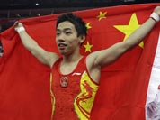 Chinese gymnast Zou Kai holds his national flag after winning the gold for the men`s floor exercise finals at the 2012 Summer Olympics.