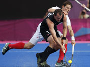 Belgium`s Felix Denayer and New Zealand`s Blair Hopping, front, battle for the ball in the men`s hockey preliminary round match at the 2012 Summer Olympics.