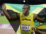 Usain Bolt, left, holds his national flag as teammate Yohan Blake, right, poses with him after Bolt`s win in the men`s 100-meter final during the athletics in the Olympic Stadium at the 2012 Summer Olympics.