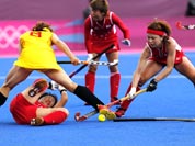 China`s Fu Baorong, left, Japan`s Keiko Manabe , left on ground, and Nagisa Hayashi vie for the ball in the preliminary round women`s hockey match at the 2012 Summer Olympics.