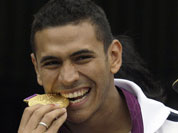 Venezuelan fencer Ruben Limardo bites his gold medal during a welcoming caravan in Caracas, Venezuela, Monday, Aug. 6, 2012. Limardo received a hero`s welcome as he returned home Monday after winning a gold medal at the London Olympics.