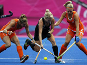 New Zealand`s Emily Naylor contests for the ball with Netherlands Kitty van Male, and Eva de Goede in the women`s hockey semifinal match at the 2012 Summer Olympics in London.